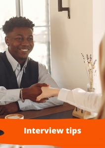 In this picture a man is shaking a woman's hand in an interview setting. They're both sitting at a table, facing each other, with a cup of coffee on the table. The man is black and has a line-up haircut. He is smiling happily. The title of this picture is "Interview Tips"